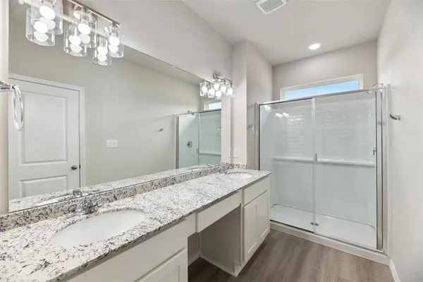 a bathroom with a granite countertop sink a mirror and a shower