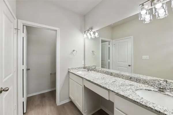 a bathroom with a granite countertop double vanity sink and a mirror