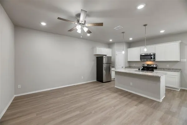 a view of kitchen with refrigerator microwave and white cabinets