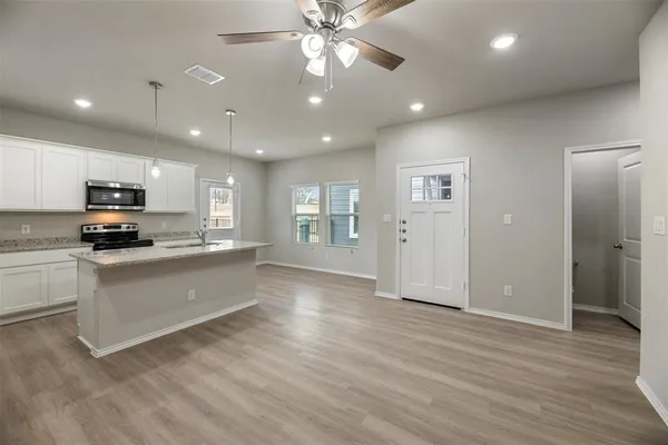 a view of an empty room with kitchen and window