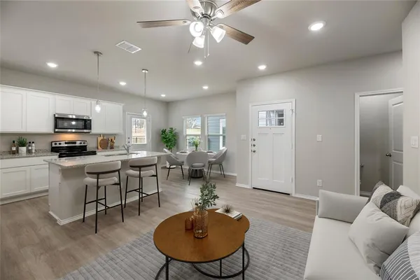 a living room with furniture kitchen view and a wooden floor