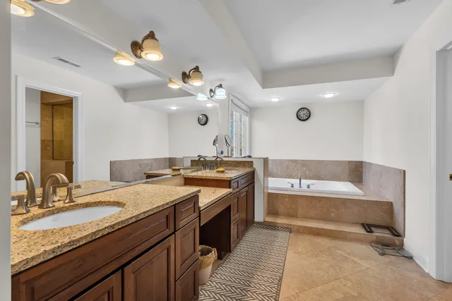 a spacious bathroom with a granite countertop sink a toilet a mirror and bathtub
