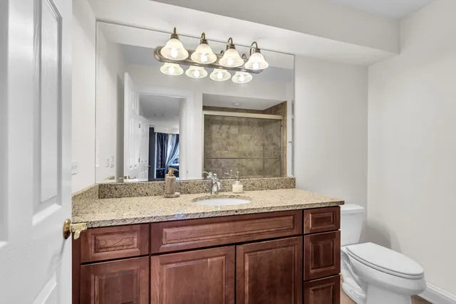 a bathroom with a granite countertop sink a toilet and a mirror