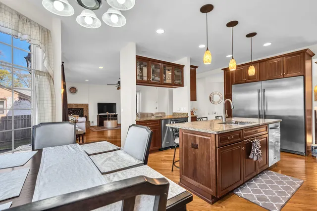 a open kitchen with stainless steel appliances granite countertop a stove a sink dishwasher and a refrigerator with the bookshelf