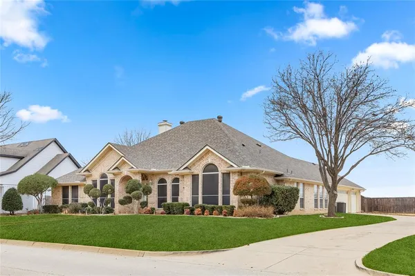 a view of a white house next to a yard with big trees