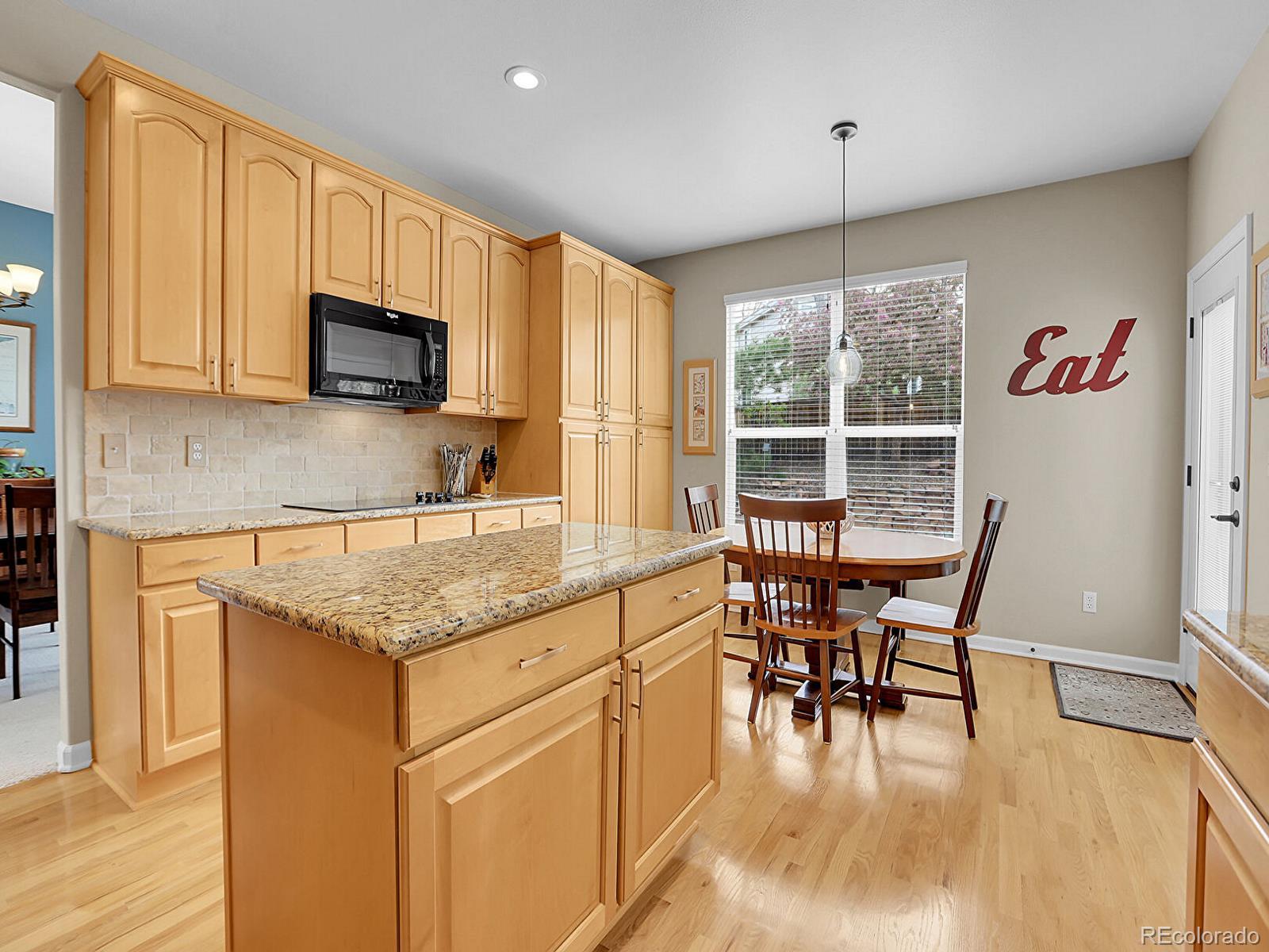 7138 Mountain Brush Circle Highlands Ranch, CO 80130 - Photo 12 of 50 a kitchen with stainless steel appliances granite countertop a stove top oven a sink a dining table and chairs with wooden floor