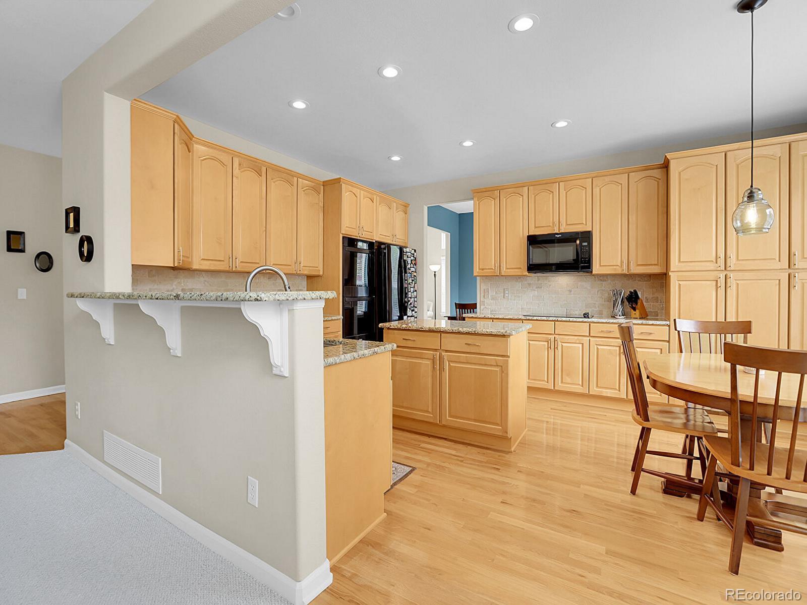 7138 Mountain Brush Circle Highlands Ranch, CO 80130 - Photo 13 of 50 a kitchen with microwave a stove top oven a sink a dining table and chairs