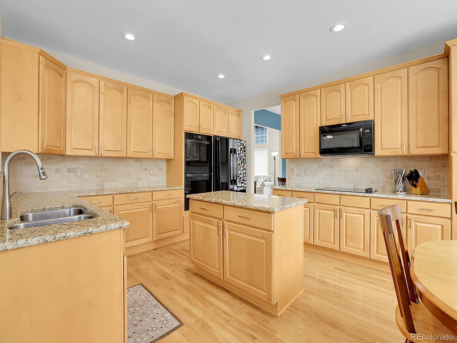 7138 Mountain Brush Circle Highlands Ranch, CO 80130 - Photo 14 of 50 a kitchen with stainless steel appliances granite countertop a stove a sink a refrigerator and white cabinets with wooden floor