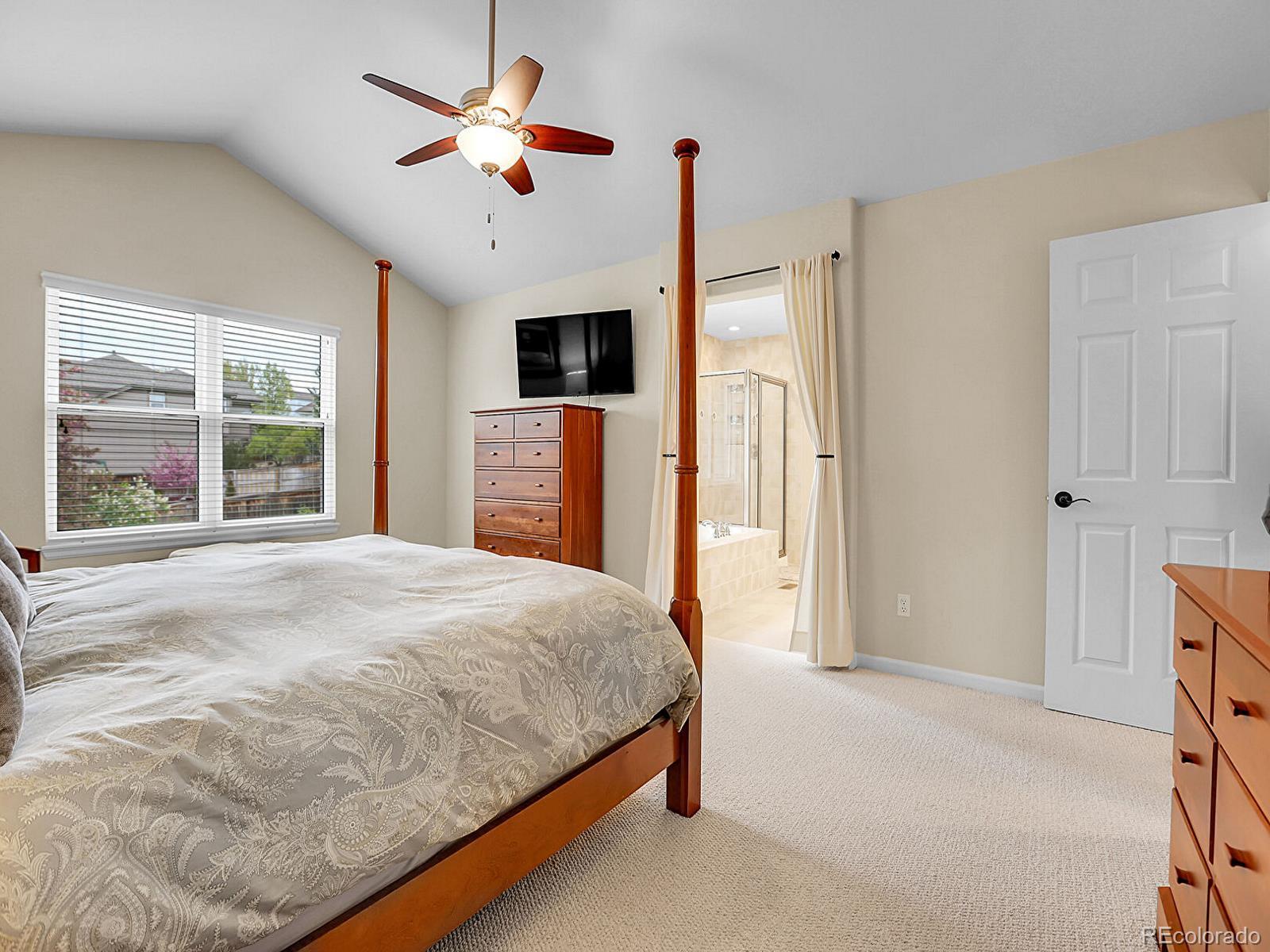 7138 Mountain Brush Circle Highlands Ranch, CO 80130 - Photo 23 of 50 a bedroom with a large bed a large window and a chandelier
