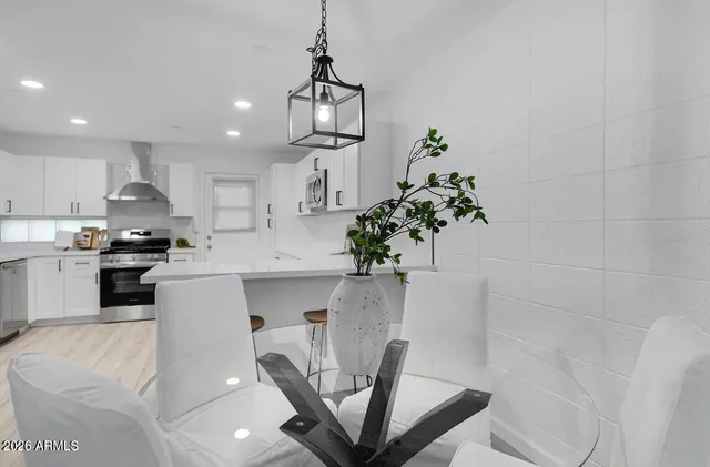 a kitchen with stainless steel appliances a dining table a microwave a stove and white cabinets