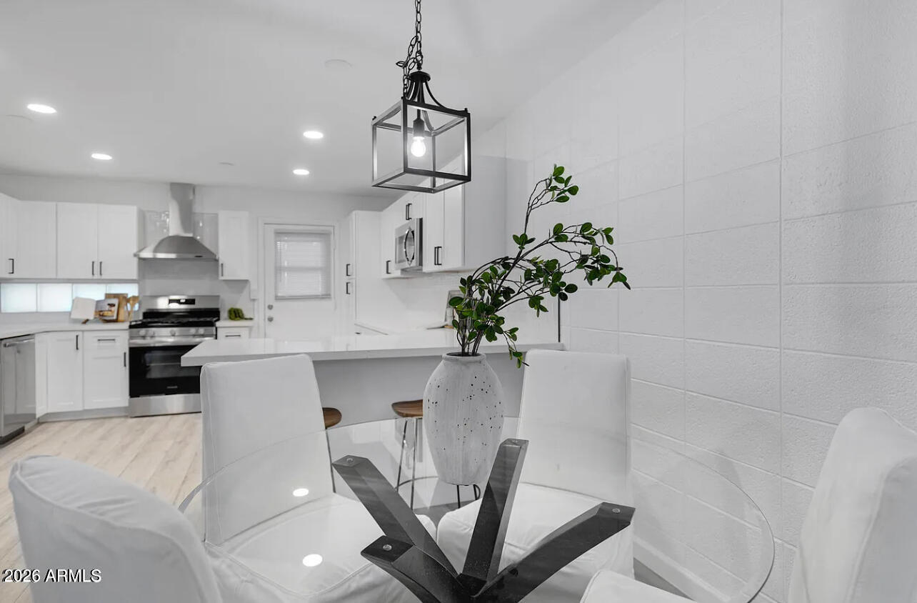 1101 East Bethany Home Road, Unit 15 Phoenix, AZ 85014 - Photo 5 of 16 a kitchen with stainless steel appliances a dining table a microwave a stove and white cabinets