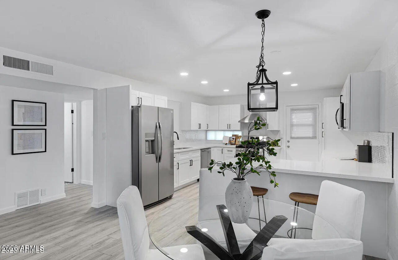 1101 East Bethany Home Road, Unit 15 Phoenix, AZ 85014 - Photo 7 of 16 a dining room with furniture and a chandelier