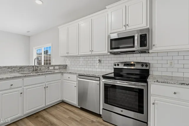 a kitchen with cabinets stainless steel appliances a sink and a wooden floor