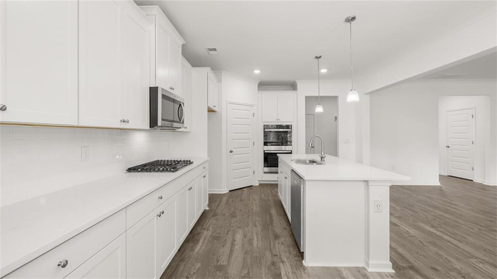1775 Goodwin Drive Hampton, GA 30228 - Photo 11 of 49 a kitchen with stainless steel appliances sink stove refrigerator and white cabinets with wooden floor