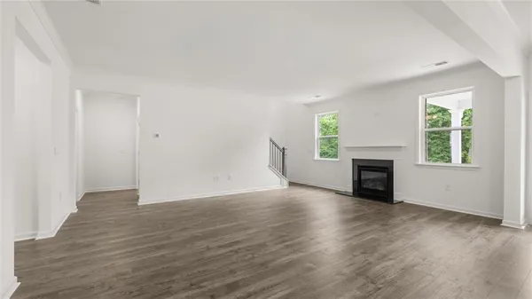 an empty room with wooden floor fireplace and windows