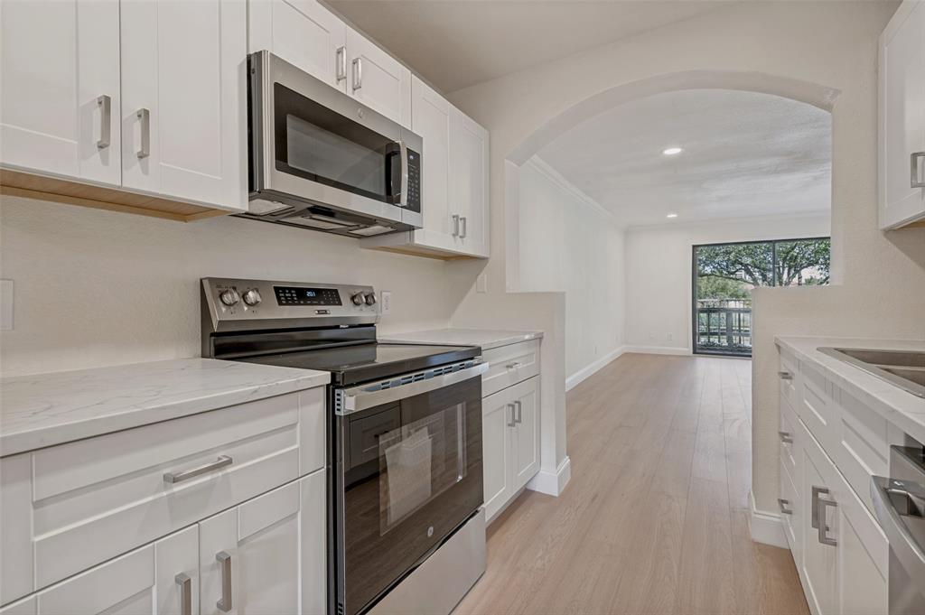 4505 North O'Connor Road, Unit 1121 Irving, TX 75062 - Photo 12 of 34 a kitchen with stainless steel appliances granite countertop a stove a microwave and white cabinets