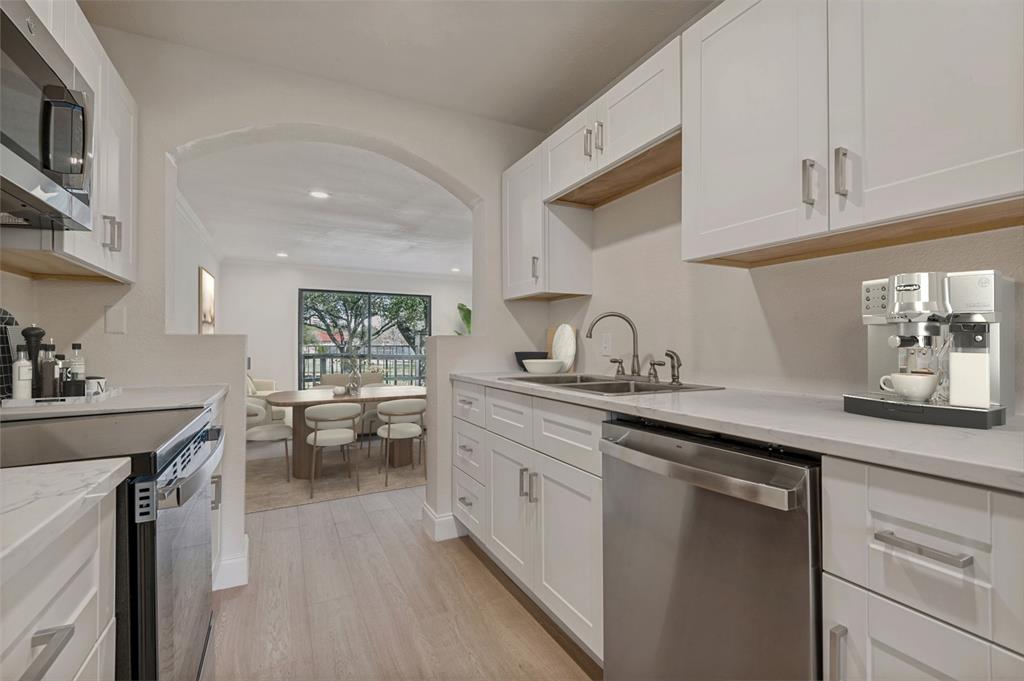 4505 North O'Connor Road, Unit 1121 Irving, TX 75062 - Photo 7 of 34 a kitchen with a sink dishwasher stove and white cabinets with wooden floor
