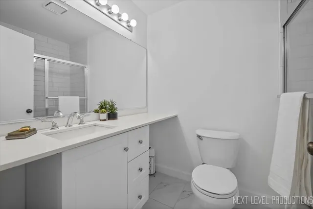 a bathroom with a granite countertop sink a toilet and a mirror