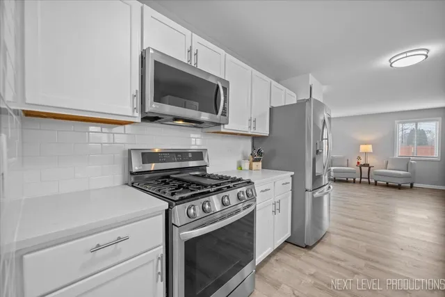 a kitchen with stainless steel appliances white cabinets and a stove top oven