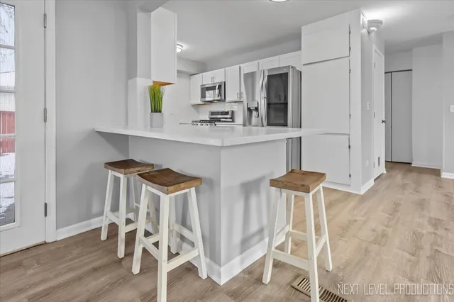 a kitchen with stainless steel appliances kitchen island granite countertop refrigerator and chair
