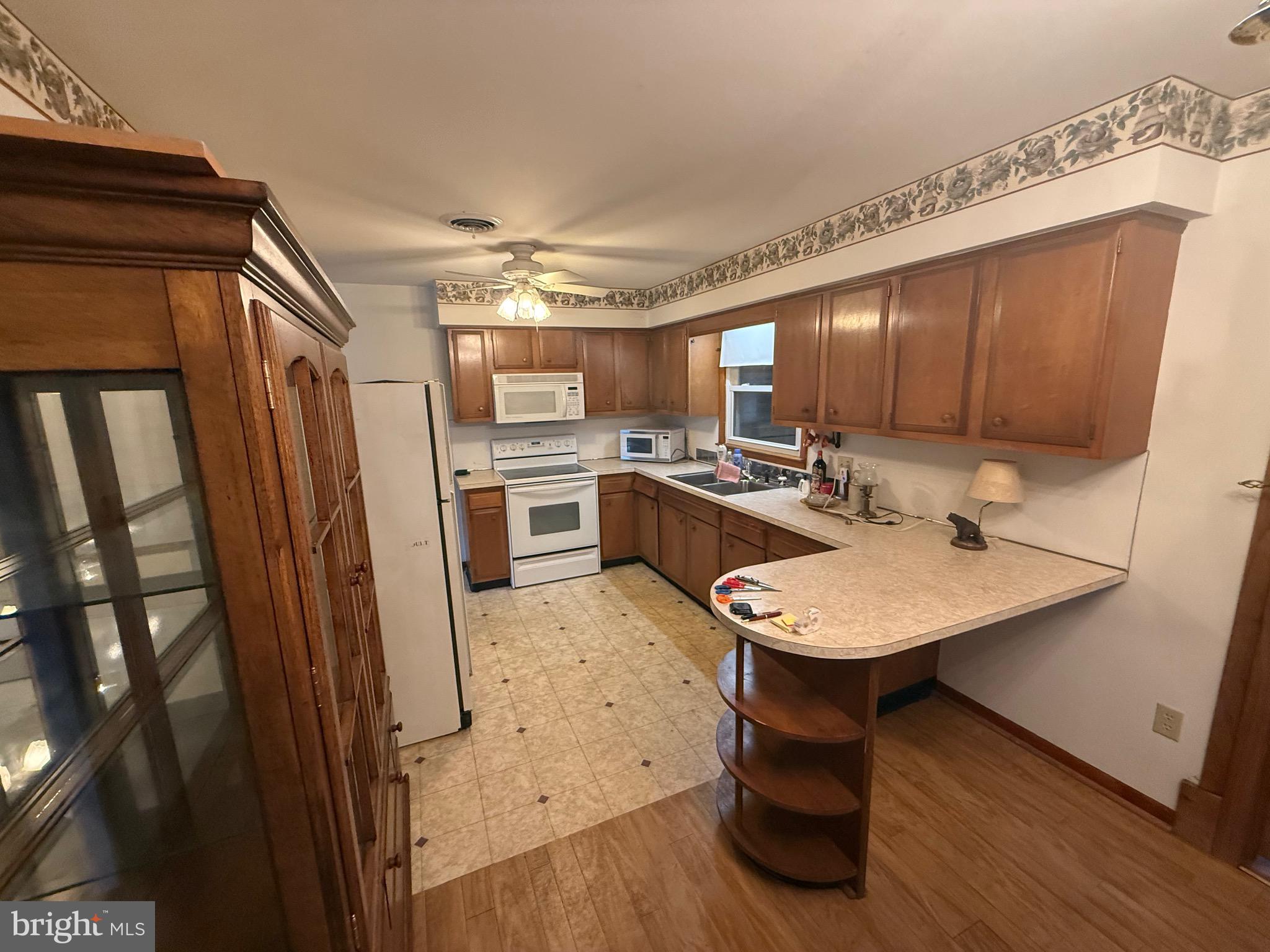 384 Fairview Drive Berkeley Springs, WV 25411 - Photo 19 of 24 a kitchen with stainless steel appliances a sink a stove a refrigerator cabinets and wooden floor