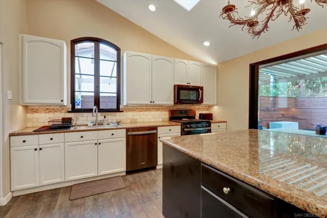a kitchen with granite countertop a stove sink and cabinets