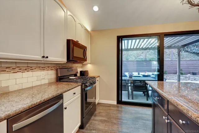 a kitchen with stainless steel appliances granite countertop a stove a sink and a microwave