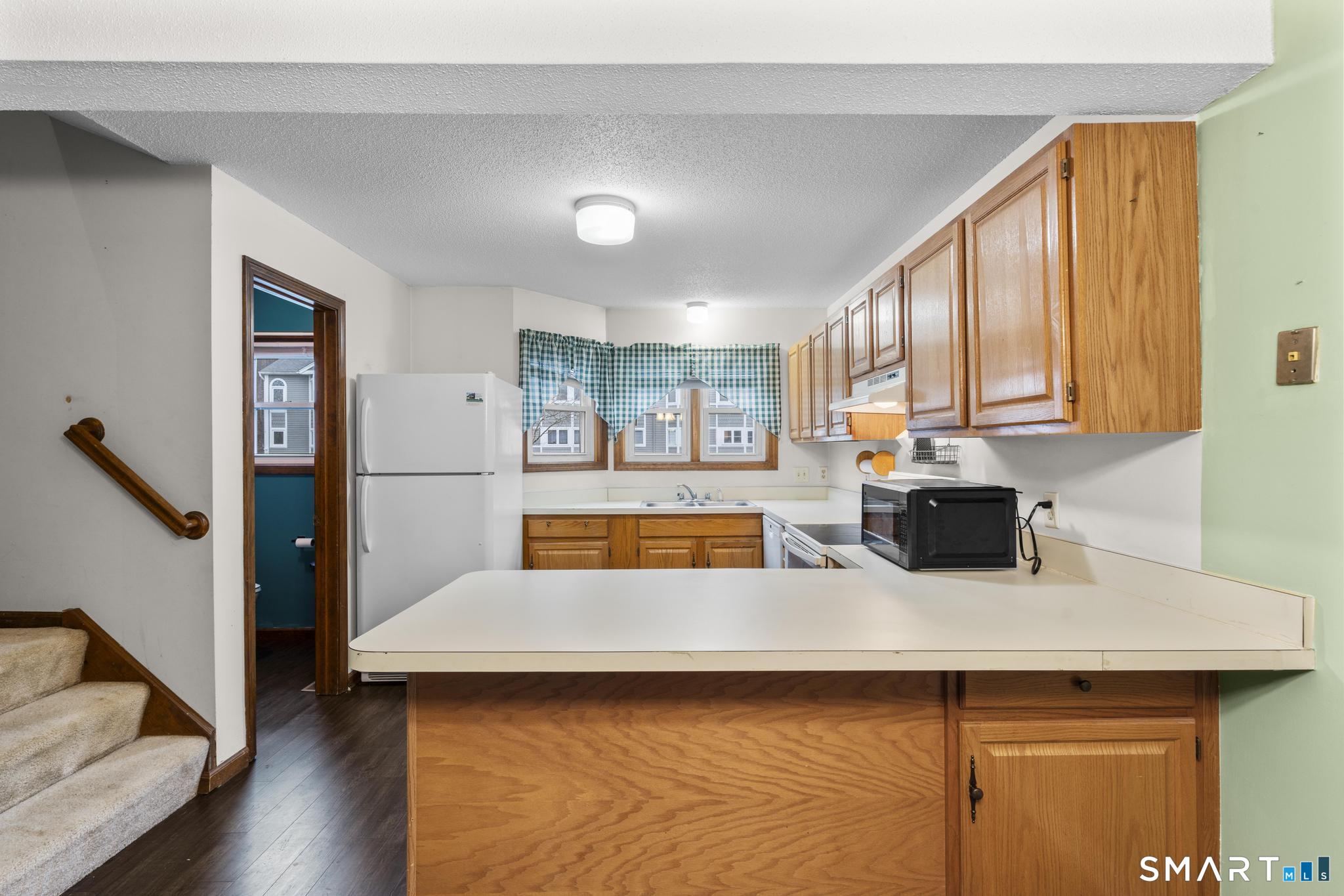 1655 North Colony Road, Unit 15 Meriden, CT 06450 - Photo 7 of 25 a kitchen with a refrigerator a sink dishwasher with a dining table and chairs with wooden floor