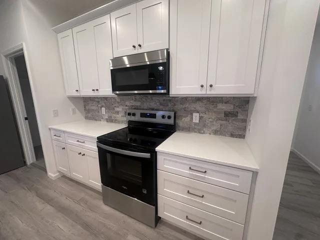 a kitchen with stainless steel appliances white cabinets and a stove a refrigerator with wooden floor