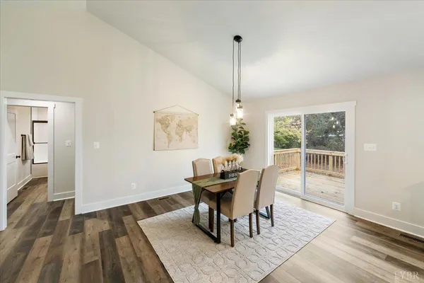 a kitchen with stainless steel appliances kitchen island granite countertop a refrigerator a stove a sink a dining table and chairs with wooden floor