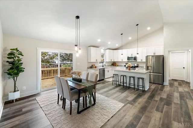 a kitchen with stainless steel appliances a refrigerator a stove a sink dishwasher a dining table and chairs with wooden floor