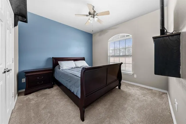 a bedroom with a bed and a flat tv screen on the dresser