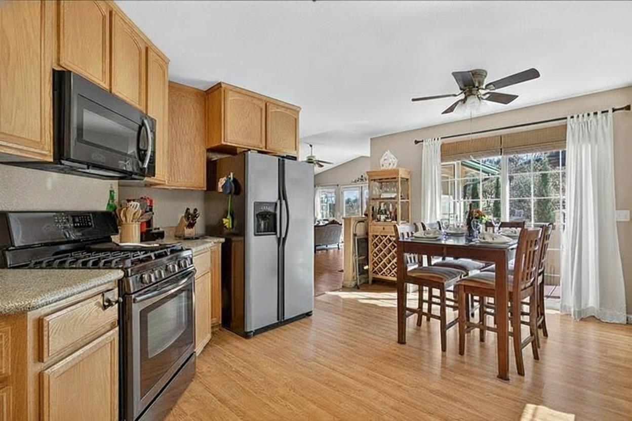 4856 Kiva Drive Copperopolis, CA 95228 - Photo 16 of 61 a kitchen with stainless steel appliances granite countertop a stove a refrigerator a kitchen island a table and chairs with wooden floor