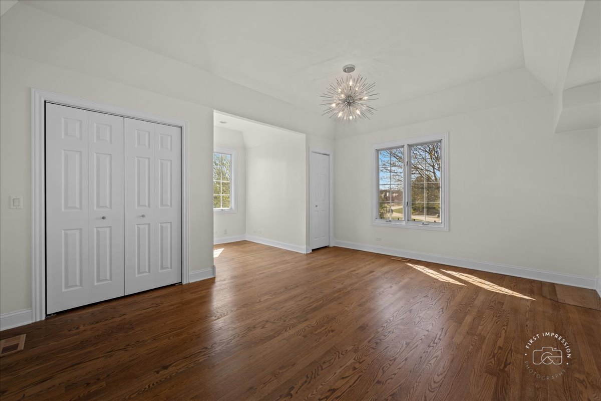 5N214 Wilton Croft Road St. Charles, IL 60175 - Photo 18 of 37 an empty room with wooden floor chandelier fan and windows
