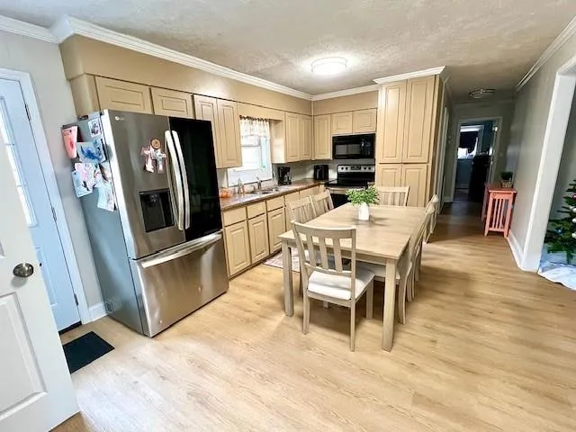 a kitchen with stainless steel appliances a refrigerator a stove a table and chairs