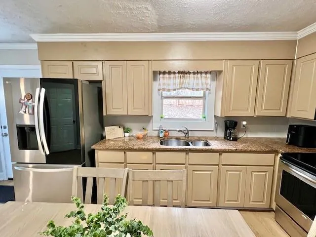 a kitchen with stainless steel appliances a sink stove refrigerator and cabinets