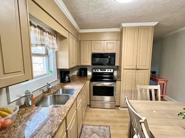 a kitchen with stainless steel appliances granite countertop a sink stove microwave and refrigerator
