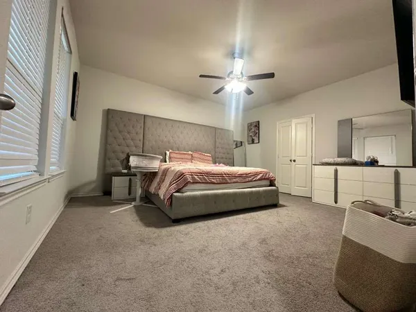 a spacious bedroom with a bed a chandelier and a large window