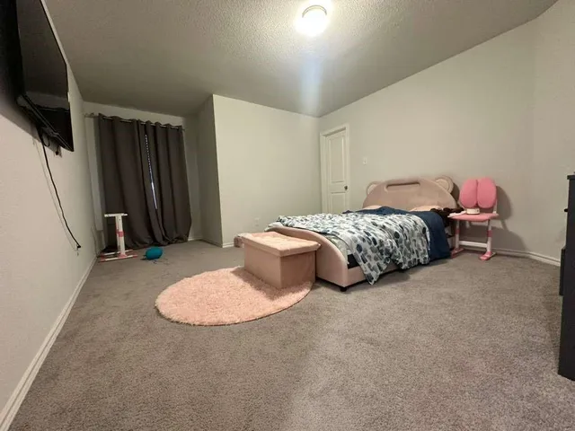 a bedroom with bed and a flat tv screen on dresser