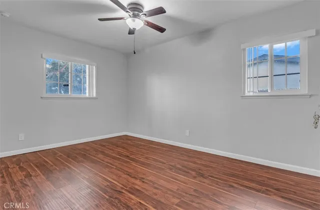 a view of empty room with wooden floor and fan