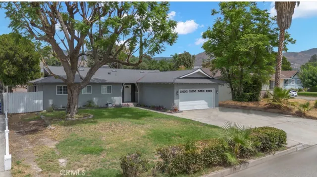 a view of a house with a small yard and a large tree