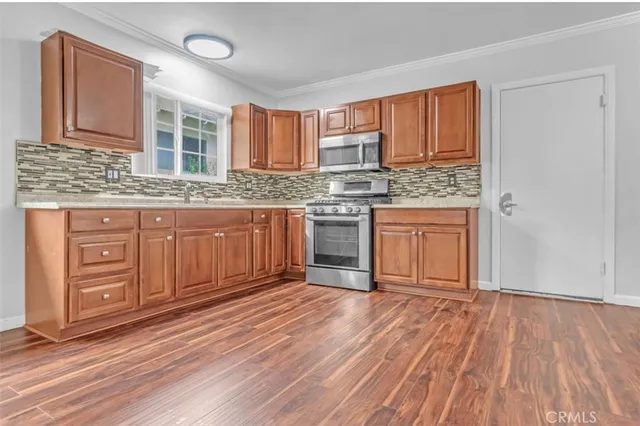 a kitchen with stainless steel appliances granite countertop a stove cabinets and wooden floor