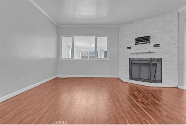 an empty room with wooden floor fireplace and windows