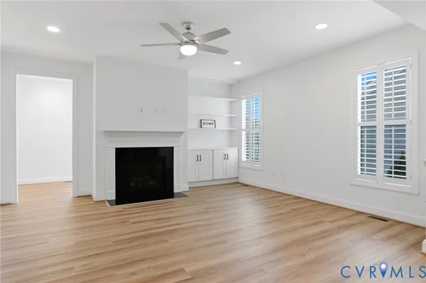 a view of an empty room with wooden floor fireplace and a window