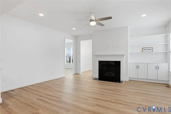 an empty room with wooden floor fireplace and windows