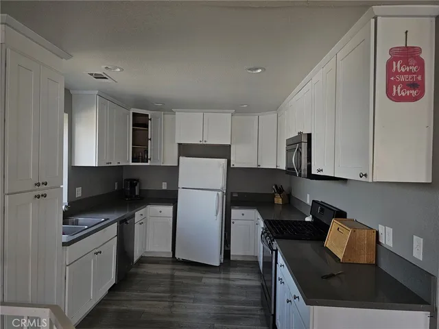 a kitchen with a refrigerator a stove top oven a sink and dishwasher with wooden floor