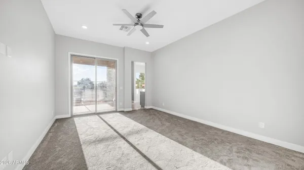 an empty room with chandelier fan and windows