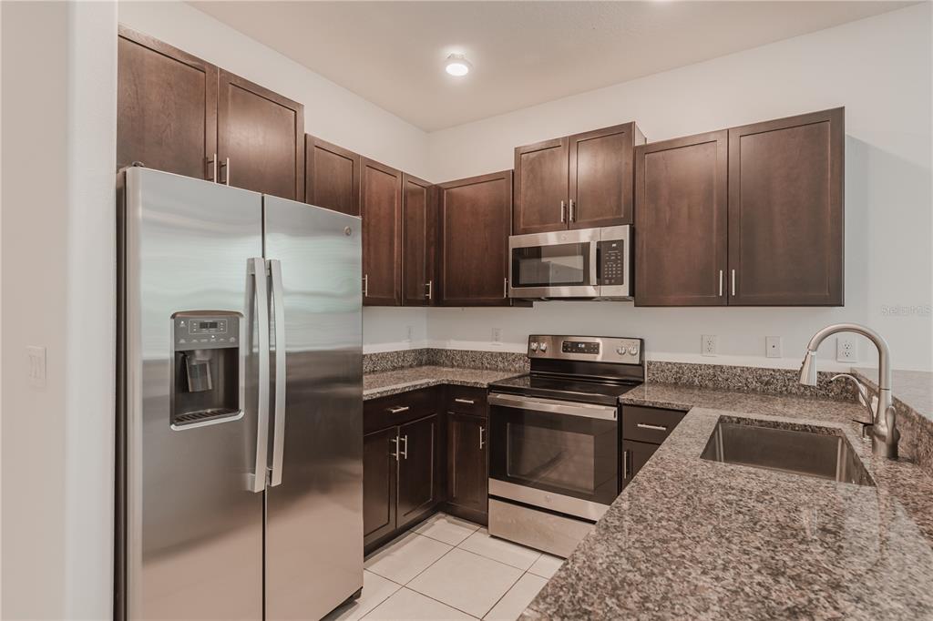 14302 Editors Note Street Ruskin, FL 33573 - Photo 19 of 44 a kitchen with granite countertop stainless steel appliances cabinets a sink and a stove
