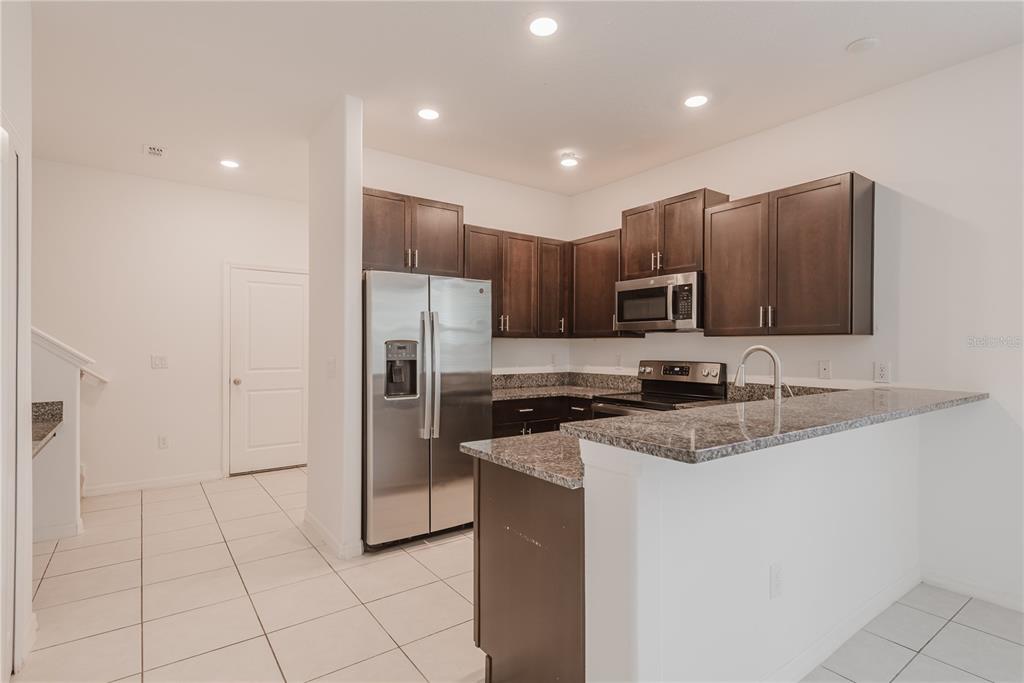 14302 Editors Note Street Ruskin, FL 33573 - Photo 20 of 44 a kitchen with stainless steel appliances granite countertop a refrigerator and a sink