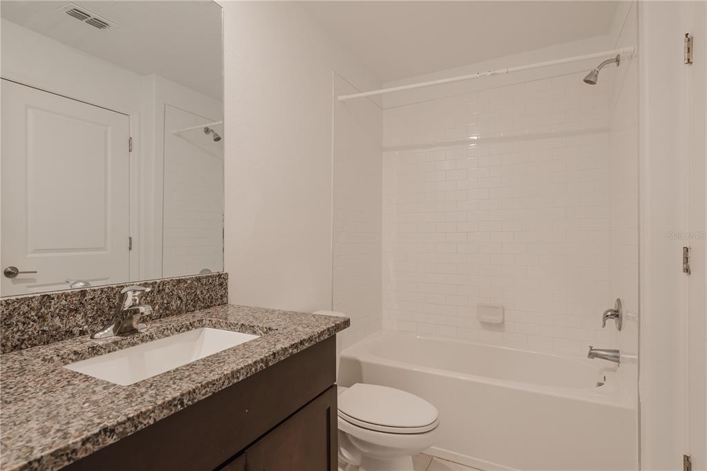 14302 Editors Note Street Ruskin, FL 33573 - Photo 9 of 44 a bathroom with a granite countertop sink a toilet and shower
